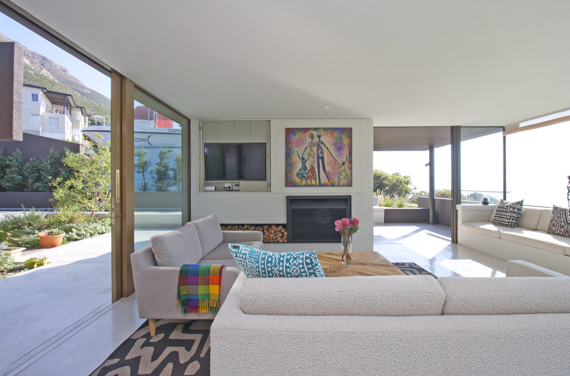 Spacious modern living room with cozy sofas, vibrant artwork, and floor-to-ceiling windows offering a scenic outdoor view.